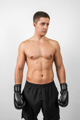 Portrait of a muscular boxer dressed in a black shorts and Boxing gloves on an isolated white background.