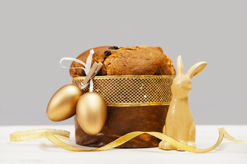 Happy Easter banner. Bunny and Italian Easter Decorated Panettone and golden eggs on white table...