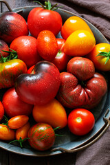 Plakat Tomatoes of various varieties and sizes on an iron tray on a wooden table.