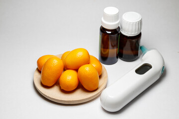 Kumquat in a wooden plate on a white background with medicines and a thermometer. Composition of vitamin C against diseases in winter. natural remedies.