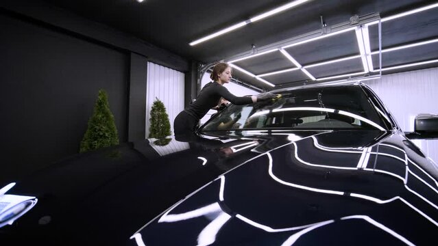 Professional car washer in black gloves wipes the car after washing and lining ceramics. Concepts of: Professional work, Various washing tools, Cleaning to shine.