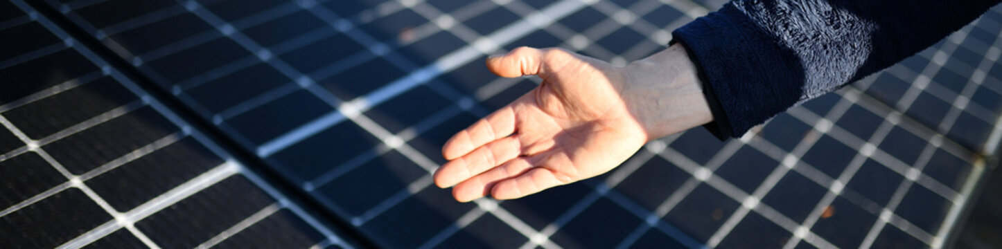Banner: Hand eines Elektro Installateurs zeigt 2023 installierte Photovoltaik PV Solar Module zur nachhaltigen Sonnenenergie Gewinnung auf dem Haus Dach