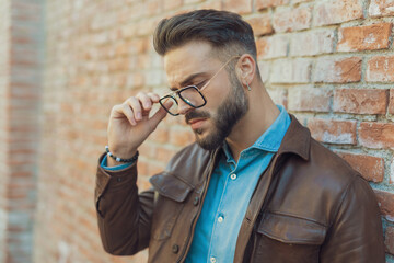 casual man arranging eyeglasses and looking down