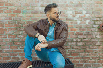 casual man sitting on a grill and looking away