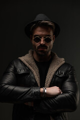 confident unshaved man crossing arms while wearing leather jacket