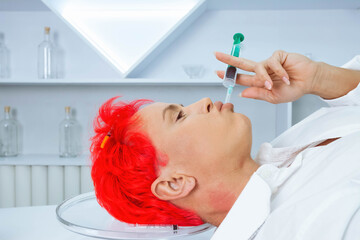 Woman with a short  bright red hair lyiong on a table with syringes and needles . mental problems, drug addiction concept.