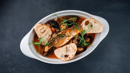 Sea bass fish fillet with squid, mussels, shrimps, tomatoes, sauce, microgreens and fried bread.