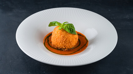 Snack breaded mozzarella cheese ball with sauce and basil.