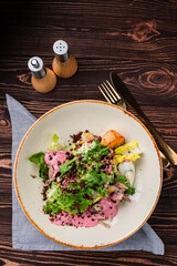 Fresh meat salad with chicken slices, eggs, arugula, lettuce and sauce.