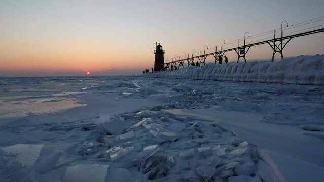 Frozen lake at lighthouse during sunset