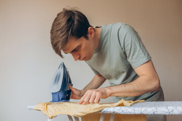 
male hands ironing a children's T-shirt on an ironing board with a blue iron