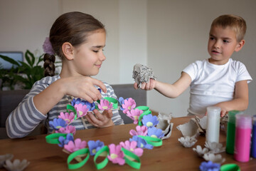 Obraz na płótnie Canvas Transformation an ordinary egg carton into a beautiful Easter flower wreath. Kids show the creative and sustainable possibilities of Zero Waste lifestyle. Reduce, reuse, and recycle. DIY with kids