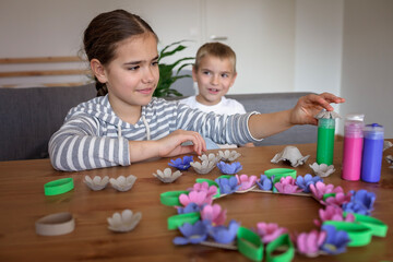 Obraz na płótnie Canvas Transformation an ordinary egg carton into a beautiful Easter flower wreath. Kids show the creative and sustainable possibilities of Zero Waste lifestyle. Reduce, reuse, and recycle. DIY with kids