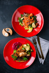 Lunch salad with salmon, cucumbers, lettuce, tomatoes and fried pork fillet with cucumbers, pickled onions and parsley