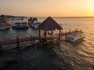 Sunrise in Calm Mexican town Bacalar, Quintana-Roo, Mexico at morning time. Docks on a pillars with Boats in Lagoon