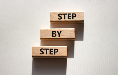 Step by step symbol. Wooden blocks with words Step by step. Beautiful white background. Business concept. Copy space.