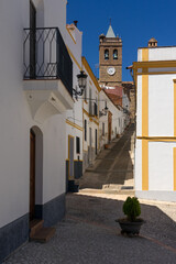 Beautiful street with its typical white facadesand the San MArtin church in the background in Almonaster La Real in Huelva province, Andalucia, Spain.