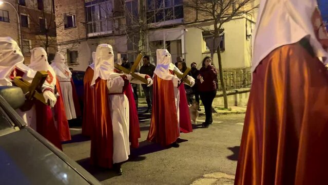 Soria, Spain - April 11, 2022: Video of Holy Week procession of hooded people down the street carrying the Christ on Holy Monday