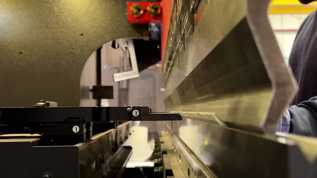 video of side view of a metal bending machine of a worker working and bending sheets
