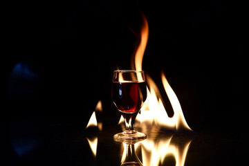 Naklejka na ściany i meble shot of cognac drink with fire in the background glass of red wine