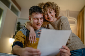 Young man male student teenager and his mother celebrate scholarship read mail letter happy exited...