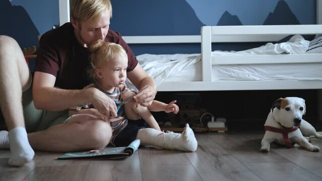 father and son glue stickers on the boy's bandaged leg