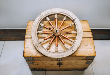 An old wooden wheel from a cart lies on a chest, a treasure chest. An ancient find, an invention from the past, vintage.
