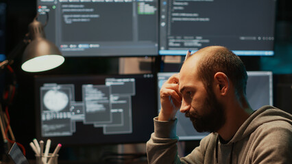 Thoughtful IT engineer brainstorming ideas in office, programming script and source code. Pensive...