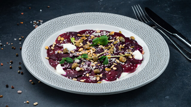 An appetizer of beetroot, hard cheese, pumpkin and sunflower seeds, capers, sour cream and microgreens.