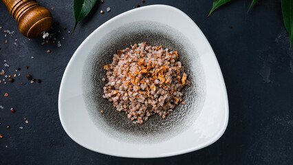 Boiled buckwheat porridge with fried onions in a plate.