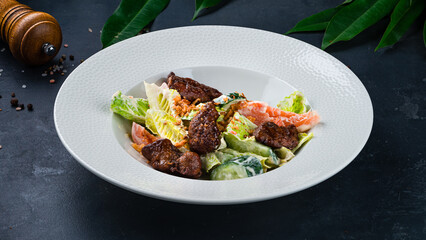 Fresh calad with fried chicken, cucumber, lettuce, tomatoes, onion on a dark table.