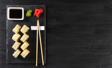 Sushi roll Philadelphia with salmon, sesame seeds, avocado, cream cheese on black slate background. Sushi menu, rolls served on white dish and soy sauce. Traditional Japanese cuisine food.