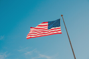 American Flag waving in blue sky, copy space