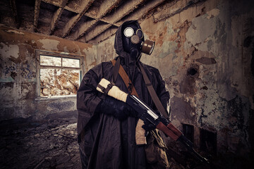 Post apocalyptic warrior  in gas mask wandering through abandoned settlement.