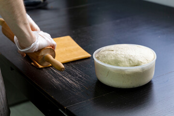 Baker preparing homemade dough and flattening it out with rolling pin