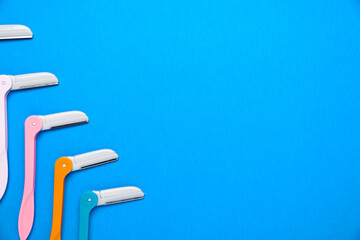 women's razors with plastic handles of different colors on a blue background. Space for text.