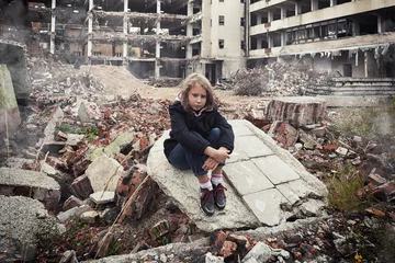little girl sitting among ruins of house. Refugees concept. War crisis in Ukraine. Humanitarian disaster concept. © phant
