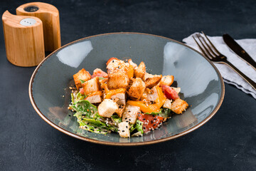Italian dish Caesar salad with chicken, parmesan cheese, lettuce, tomatoes, croutons.