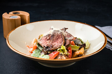 Beef salad with tomatoes, parmesan cheese, pickled cucumber, lettuce and sauce.