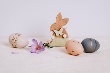 Obraz premium Wooden toy bunny, saffron flower and painted Easter eggs on white table. Easter holiday concept, closeup