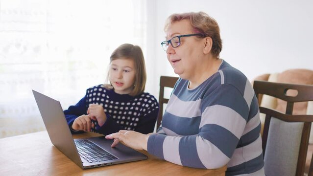 the special bond between a grandmother and her granddaughter as they sit together at home, working on a laptop. The kid is explaining a new concept to her grandmother, to learn from her grandchild
