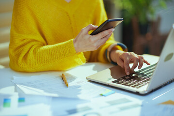 Stylish business owner woman in green office using smartphone