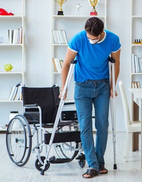 Young Man Recovering After Surgery At Home With Crutches And A W