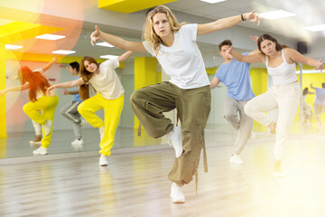 Naklejka premium Portrait of expressive teens dancer in choreographic studio with dancing teenagers in background