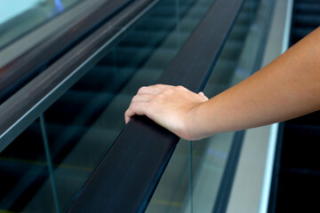 Hand holding escalator handrail in shopping mall or building