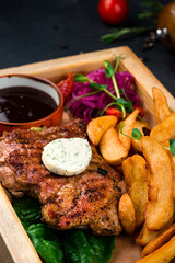 Pork fillet steak with potato wedges, marinated red onion and sauce.