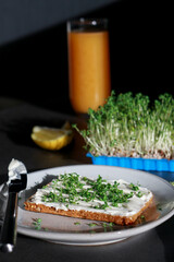 a slice of homemade bread with vegan cream cheese and fresh watercress, dark grey marble table