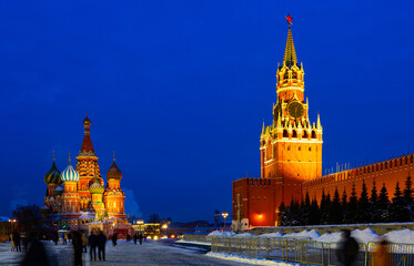 Fototapeta premium View of illuminated Spasskaya Tower and Saint Basils Cathedral on Red Square in Moscow on winter evening, Russia