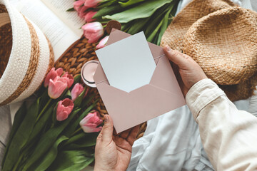 Woman's hands holding a letter in craft envelope. Pink background, Mother's day concept. Place for your text