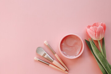 Makeup brushes, eye patches on a pink background, space for your text